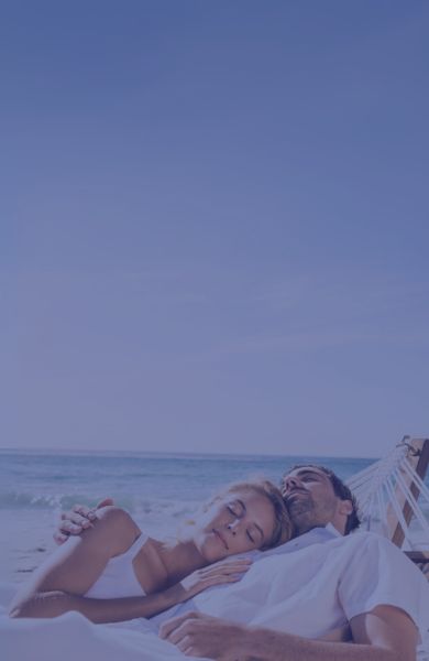 Younger couple laying in hammock at the beach | SleepTest.co.uk
